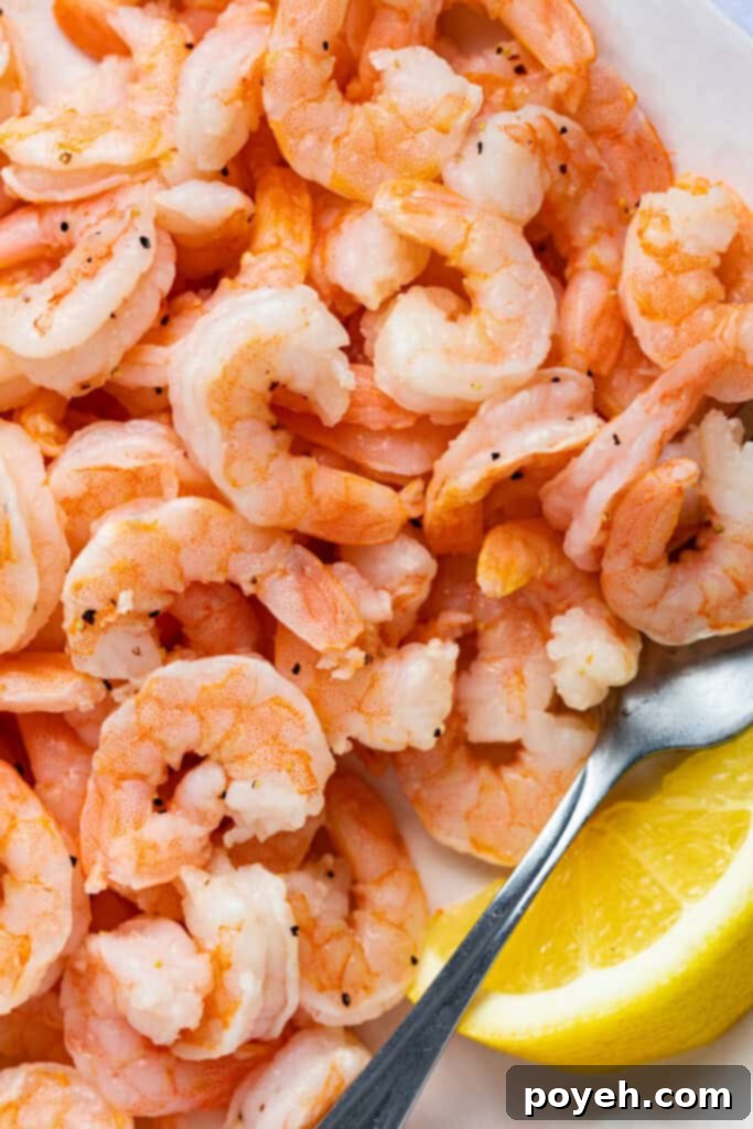 Close-up image of cooked shrimp garnished with a fresh lemon wedge.
