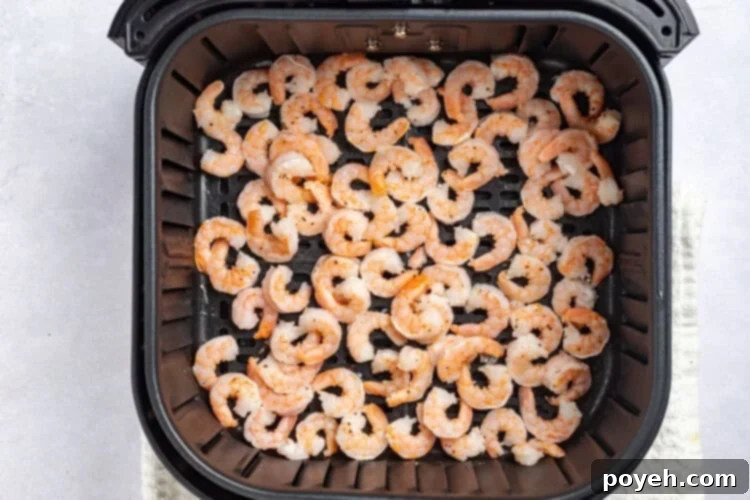 Pre-cooked shrimp cooking in an air fryer basket.