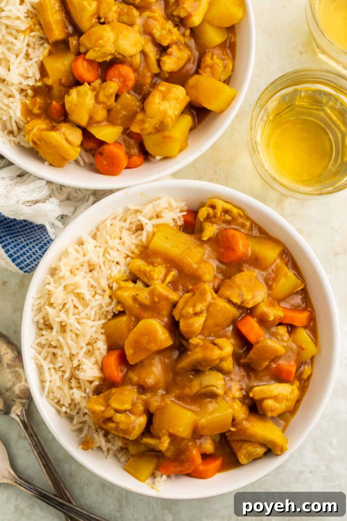 Two bowls of Instant Pot Japanese curry served with white rice on a rustic wooden table.