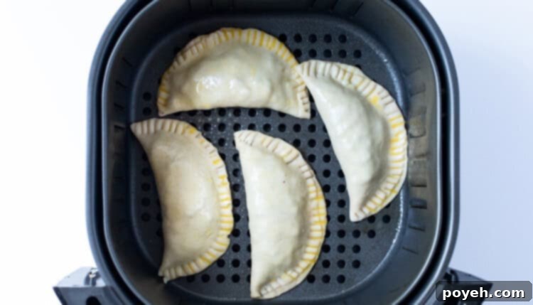 Unbaked empanadas in an air fryer basket