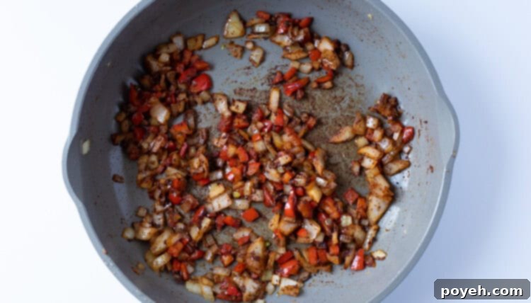 Onion and bell pepper with spices in skillet