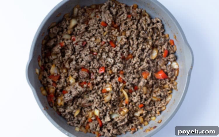 Ground beef with onion, beef broth, bell pepper, and spices in skillet