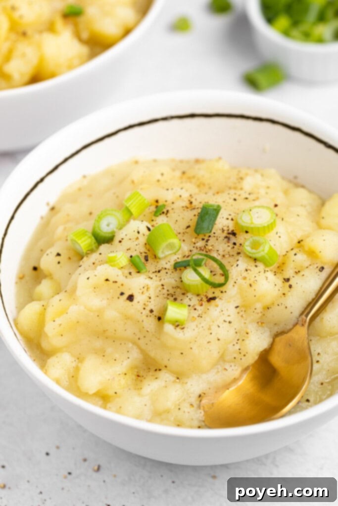 Two cozy bowls of creamy stewed potatoes, each topped with a sprinkle of fresh green onions and a generous grind of black pepper, ready to serve.