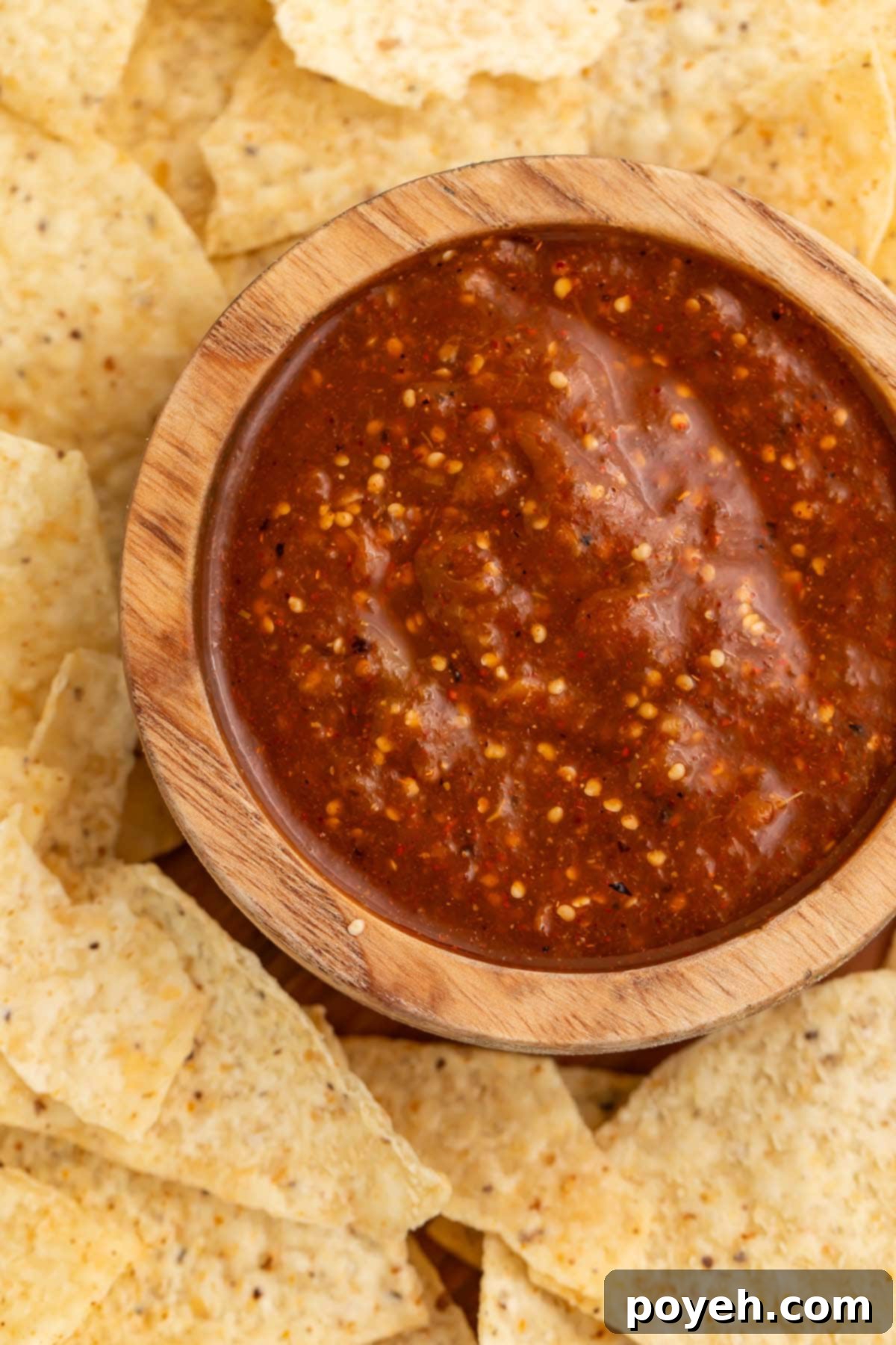 A bowl of tomatillo red chili salsa on a platter surrounded by tortilla chips.