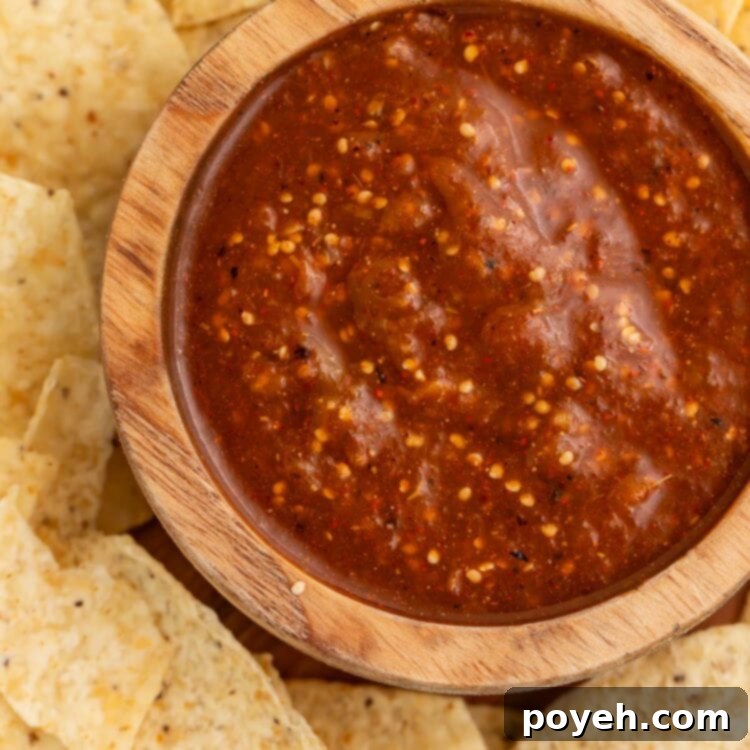 A bowl of tomatillo red chili salsa on a platter surrounded by tortilla chips.