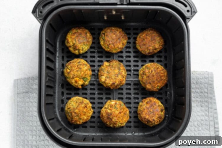 Falafel balls placed in an air fryer basket, lightly sprayed with oil