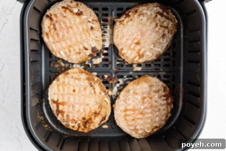 Frozen turkey burger patties cooking in an air fryer basket.