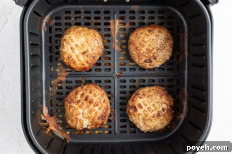 Pre-made turkey burger patties cooking in an air fryer basket.