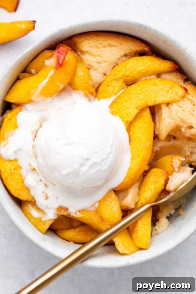 vegan peach cobbler in a bowl with a scoop of vegan vanilla ice cream on top