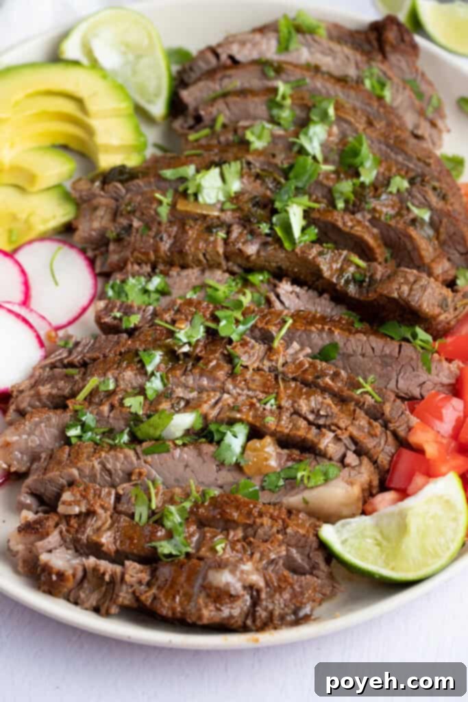 Sliced Instant Pot carne asada on a white plate surrounded by vibrant vegetables