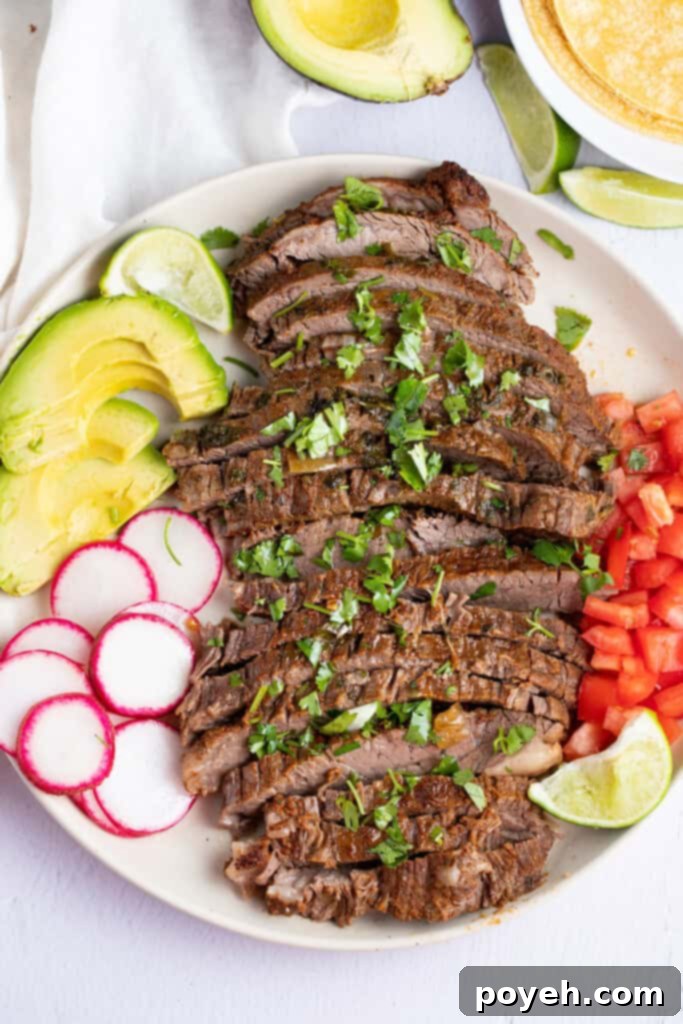Zoomed out photo of deliciously sliced Instant Pot carne asada on a white plate sitting on a clean white table