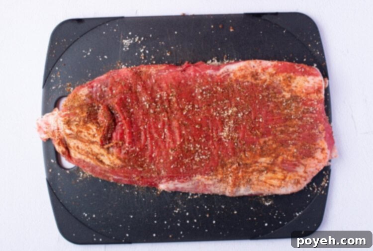 Seasoned flank steak on a cutting board, ready for cooking