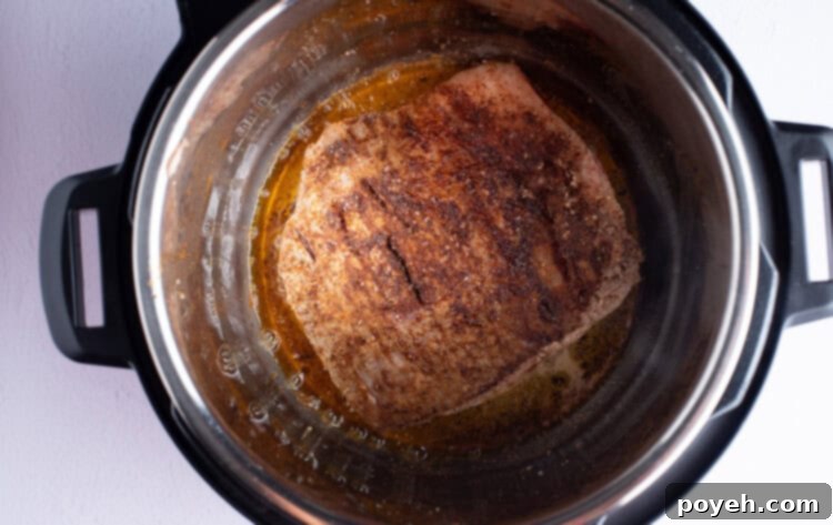Seasoned flank steak sizzling in olive oil inside the Instant Pot