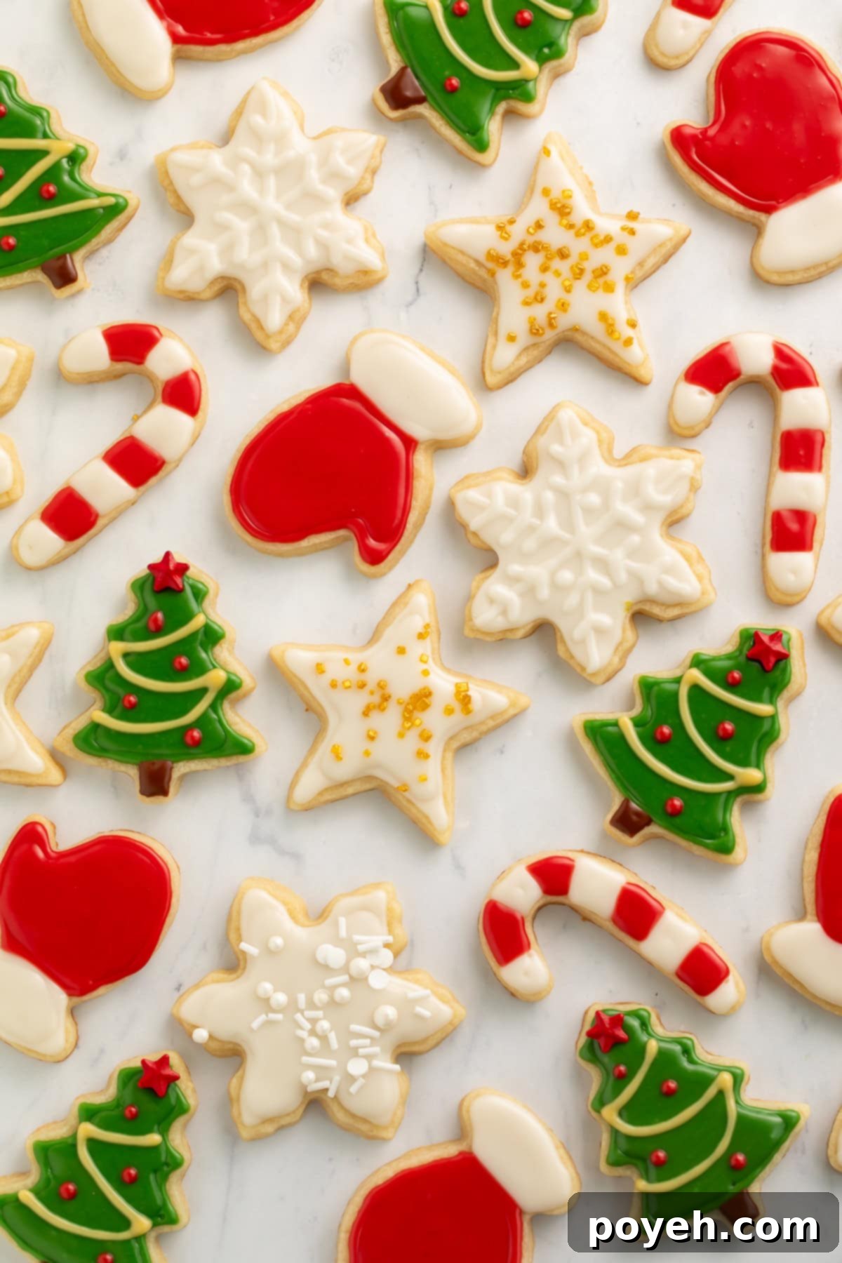 Various vegan decorated Christmas cookies on a white marble background.